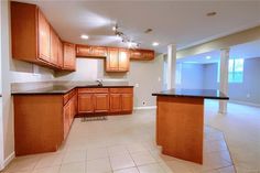 an empty kitchen with wooden cabinets and black counter tops in the middle of a living room