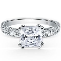 a princess cut diamond engagement ring with filigrees on the sides and an engraved band