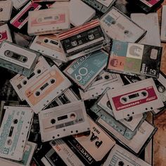 a pile of cassettes sitting on top of a wooden table next to each other