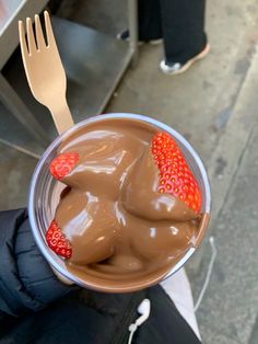 a person holding a plastic cup filled with chocolate and strawberries