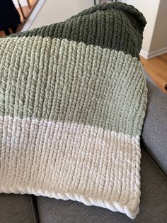 a green and white blanket sitting on top of a gray couch next to a stair case