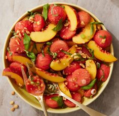 a bowl filled with sliced peaches and green leaves on top of a marble table