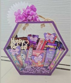 a purple basket filled with candy and flowers