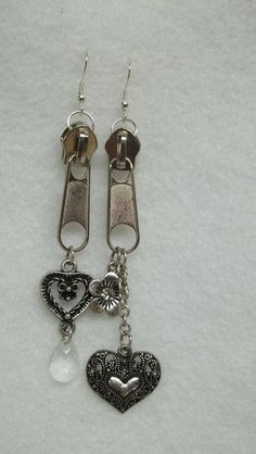 two heart shaped charms are attached to silver earwires on a white background with clippings