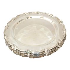 an antique silver plate with beading on the rim and handles, set against a white background