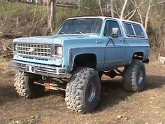 a large blue truck parked on top of a dirt field