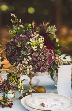 a table topped with plates and vases filled with different types of flowers on top of it