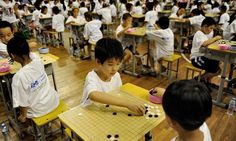 young children play with toys in a classroom filled with students sitting at desks and wearing white t - shirts