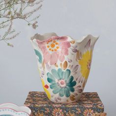 a flowered vase sitting on top of a table next to a plate and bowl