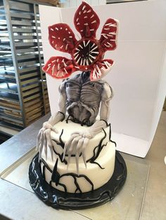 a white and black cake with red decorations on it's top sitting on a table