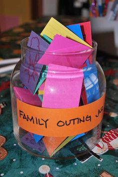 a glass jar filled with lots of colorful sticky notes on top of a green table cloth