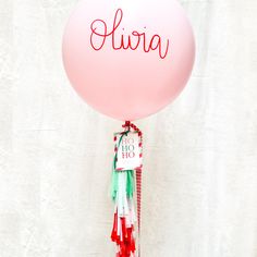 a pink balloon with the word aliria on it and tassels attached to it