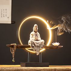 a buddha statue sitting on top of a wooden table next to a burning incense pipe