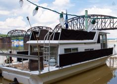 a houseboat is docked on the water with a bridge in the backgroud