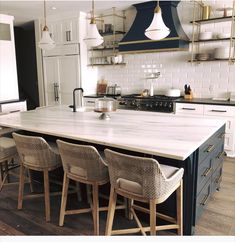 a kitchen island with four chairs around it and an oven in the backround