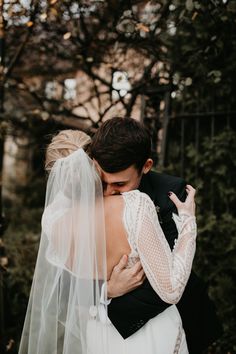 a bride and groom embracing each other in front of trees