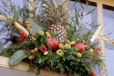 an arrangement of fruit and greenery on a window sill with pineapples