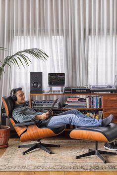 a man sitting in an orange recliner with headphones on and his feet up