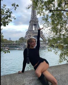 a woman posing in front of the eiffel tower with her legs spread out