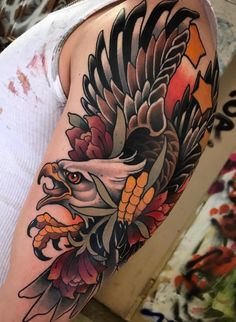 a woman with a tattoo on her arm has an eagle and flowers on it's shoulder