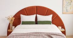 a bed with two pillows on top of it and a brown headboard in the background