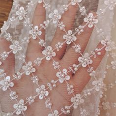 a close up of a person's hand wearing a veil with flowers on it