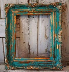 an old blue and gold frame sitting on top of a wooden floor