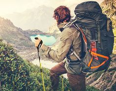 a man with a backpack is looking at the mountains and lakes in the distance while hiking