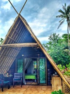 a house made out of bamboo with a green table and chairs in the front yard