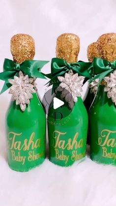 three green baby shower bottles with gold glitter tops and bows on the top are labeled tash baby shower