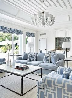 a living room filled with furniture and a chandelier hanging above the couches