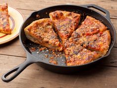 a pan filled with pizza sitting on top of a wooden table next to a plate