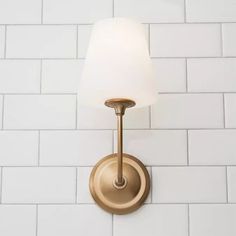 a wall light with a white shade on it's side against a white brick wall