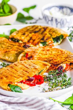 two quesadillas on a white plate with herbs