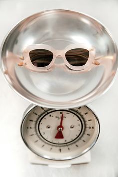 a pair of sunglasses sitting on top of a scale with the reflection of them in it