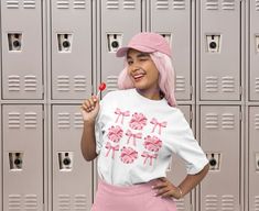 a woman standing in front of lockers with pink hair and holding a candy cane