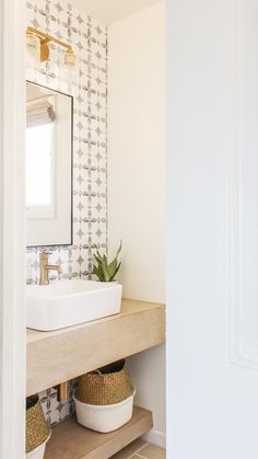 a bathroom sink sitting under a mirror next to a wooden shelf with baskets on it