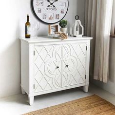 a white cabinet sitting next to a window with a clock on the wall above it