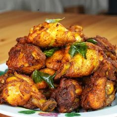 a pile of fried food sitting on top of a white and green plate next to a wooden table