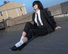 a woman sitting on the ground wearing a suit and tie