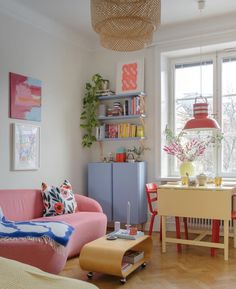 a living room filled with furniture next to a window covered in plants and bookshelves