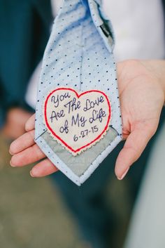 a person holding a tie with a heart on it that says you are the love of my life