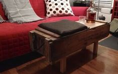 a red couch sitting next to a wooden table on top of a hard wood floor