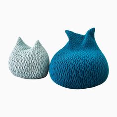 two blue and white knitted vases sitting side by side on a white background