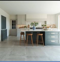 a kitchen with two stools in front of the island and an open floor plan