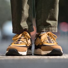 a person standing on top of a skateboard wearing brown and yellow shoes with their feet propped up