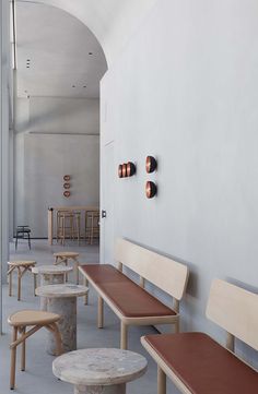 several wooden benches and stools are lined up against the wall in an empty room