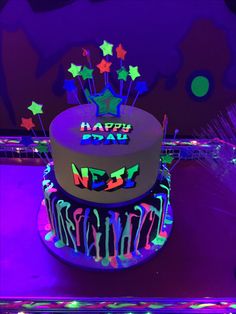 a birthday cake decorated with neon lights and stars