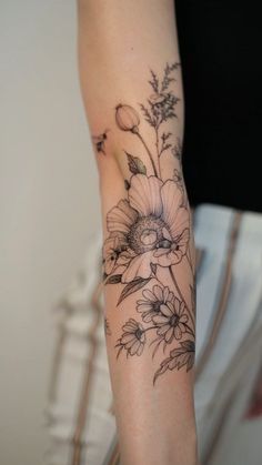 a woman's arm with flowers and leaves tattooed on the side of her arm