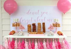 a dessert table with donuts, pastries and pink tassels on it